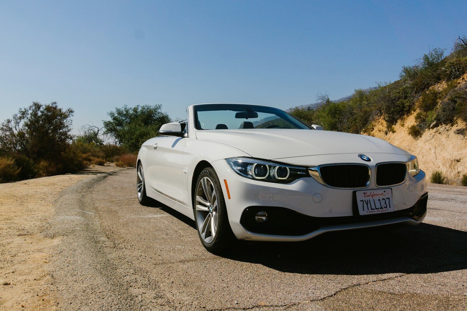 a white car is parked on the side of the road